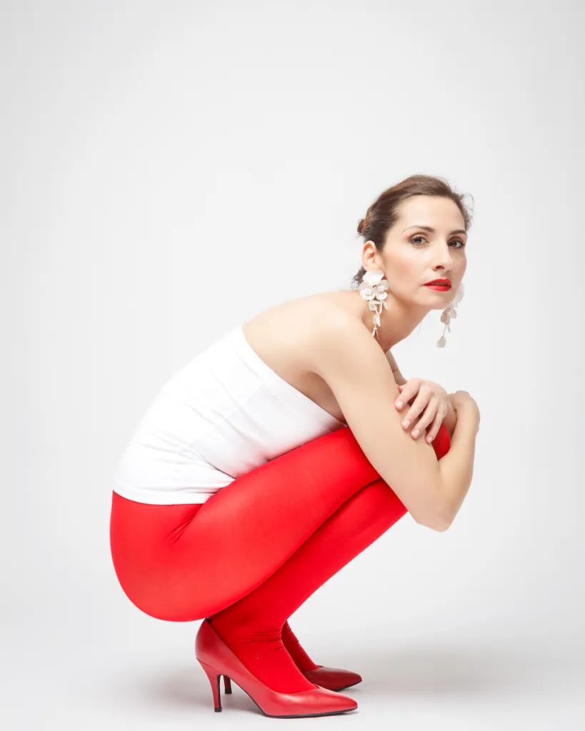 Woman poses in red tights and heels.