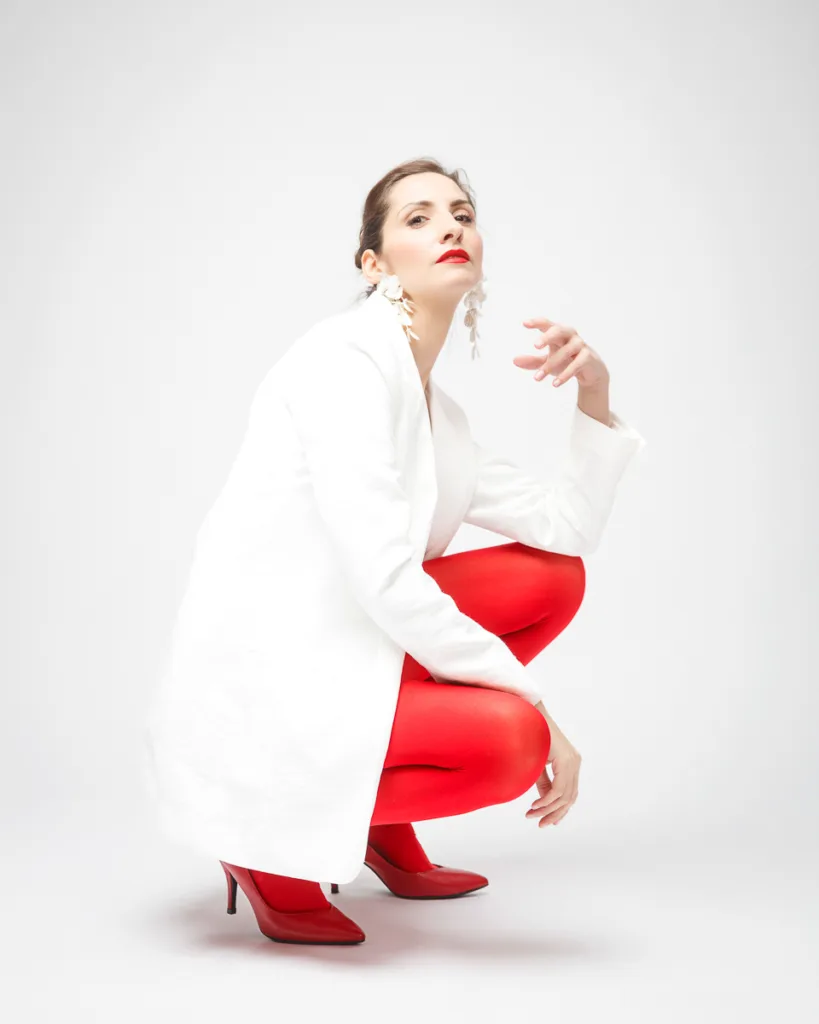 Woman in white coat, red tights, crouching pose.