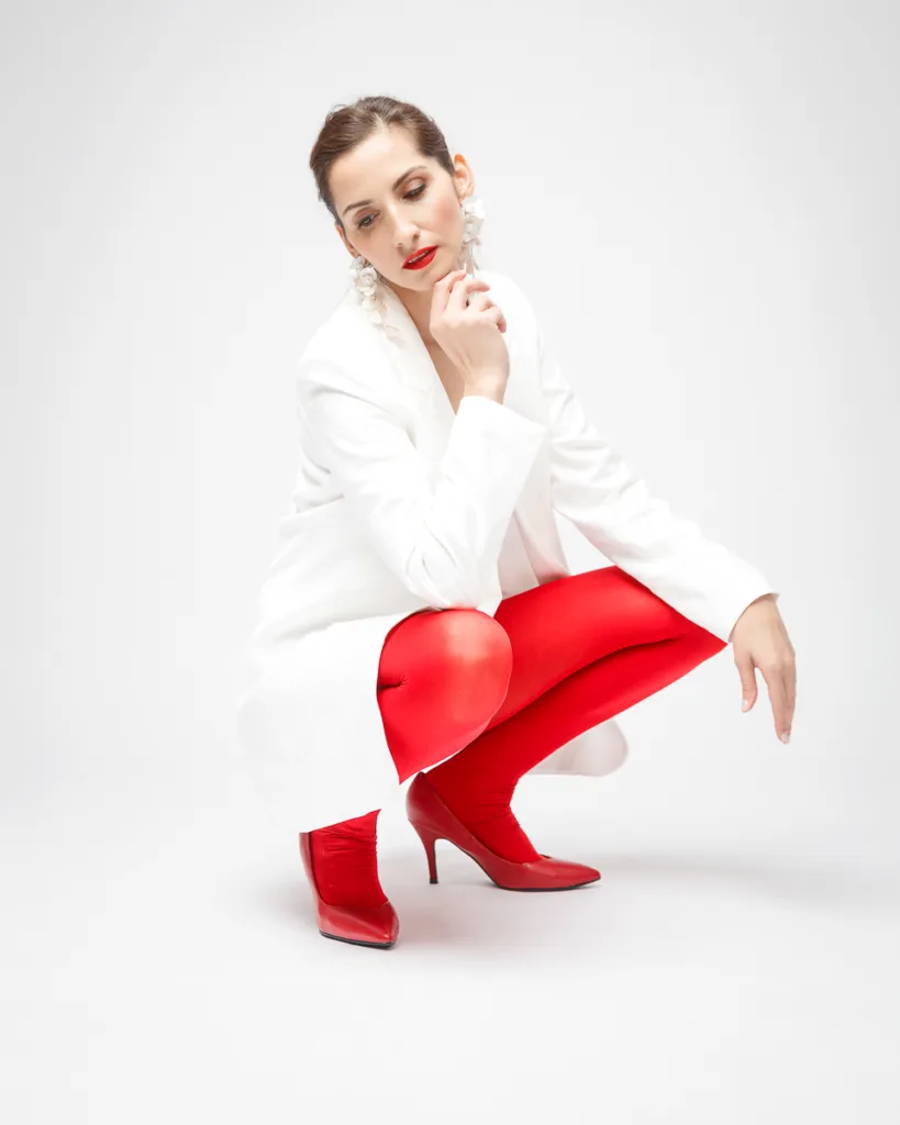 Woman in red tights and white coat squatting.