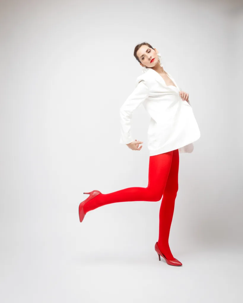 Woman in red tights and heels posing gracefully.