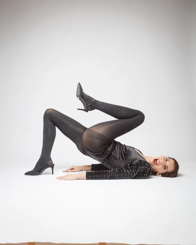 Woman in black leggings posing creatively on floor.