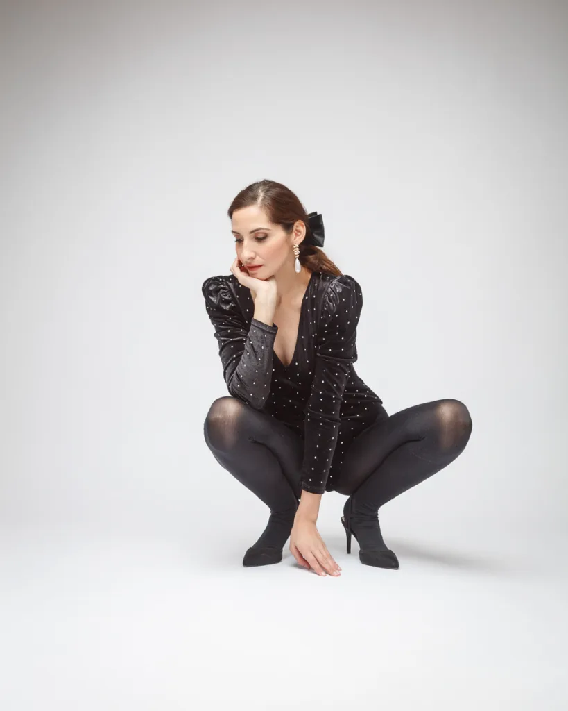 Fashionable woman squatting in black outfit