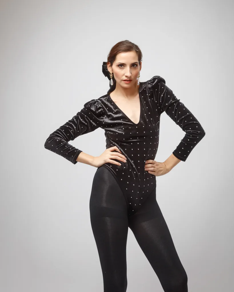 Woman in black outfit posing confidently indoors.