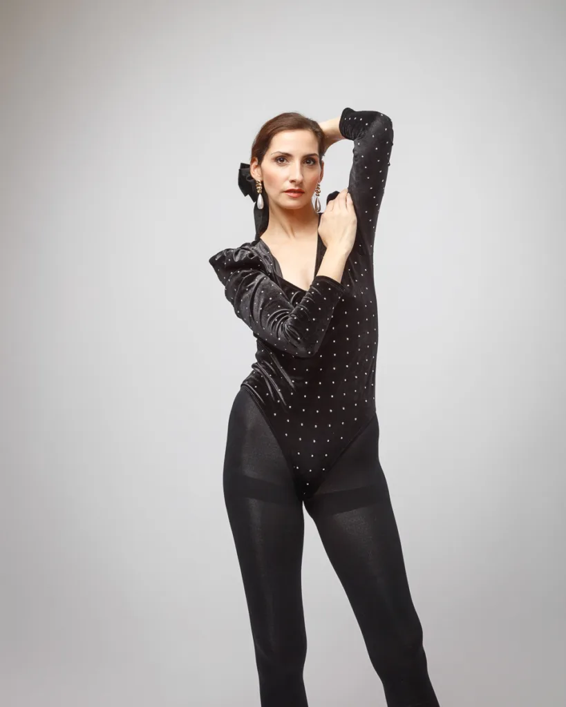Woman in black bodysuit posing gracefully.