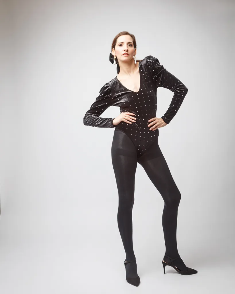 Woman in black fashion outfit posing confidently.