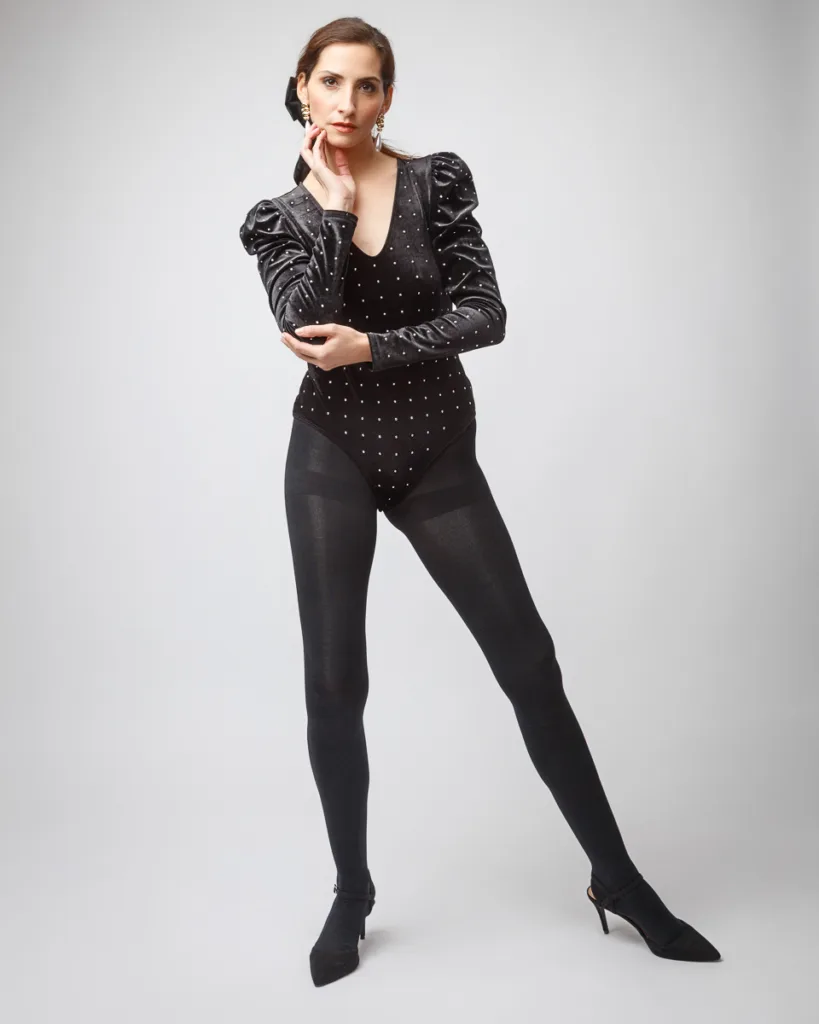 Woman in black polka dot bodysuit and tights.