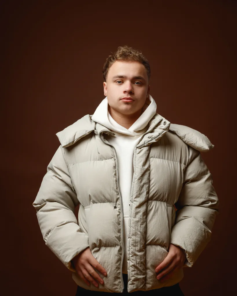Person wearing beige puffer jacket in studio setting.