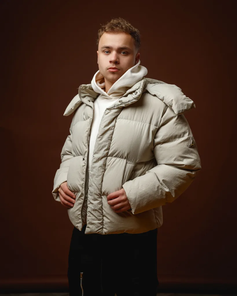 Person in white winter jacket, brown background.