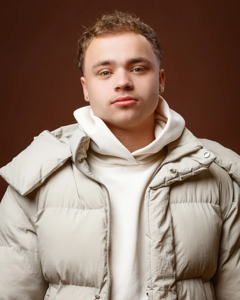 Man in beige puffer jacket and hoodie.