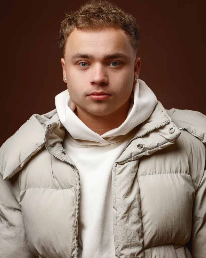 Young person in beige puffer jacket and hoodie.