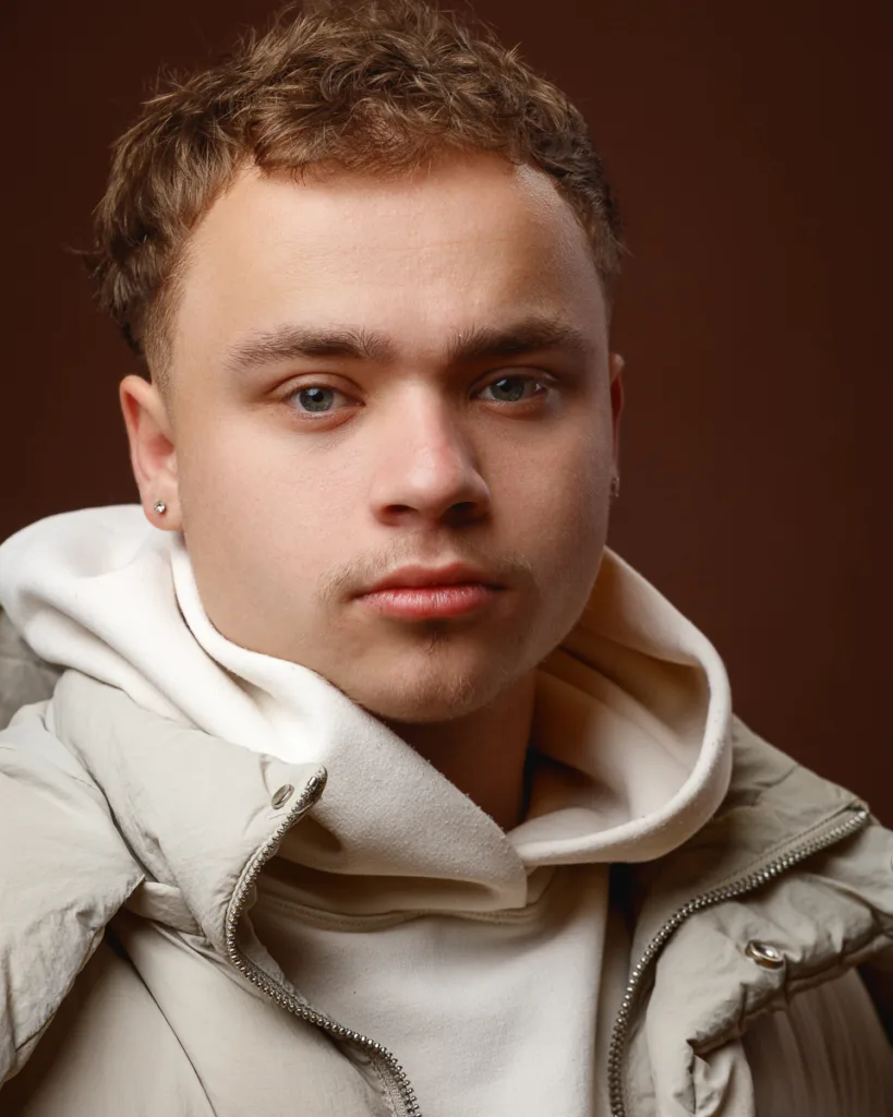 Young man in beige hooded jacket, close-up portrait.