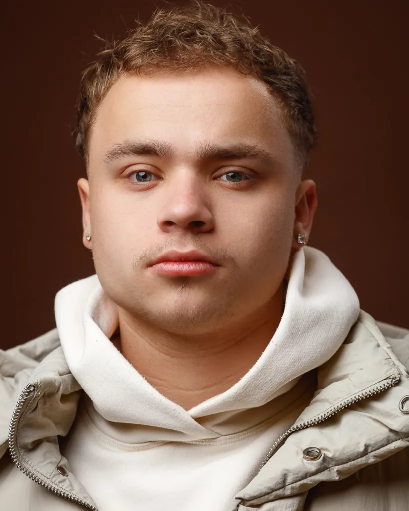 Man wearing white hoodie, brown background.