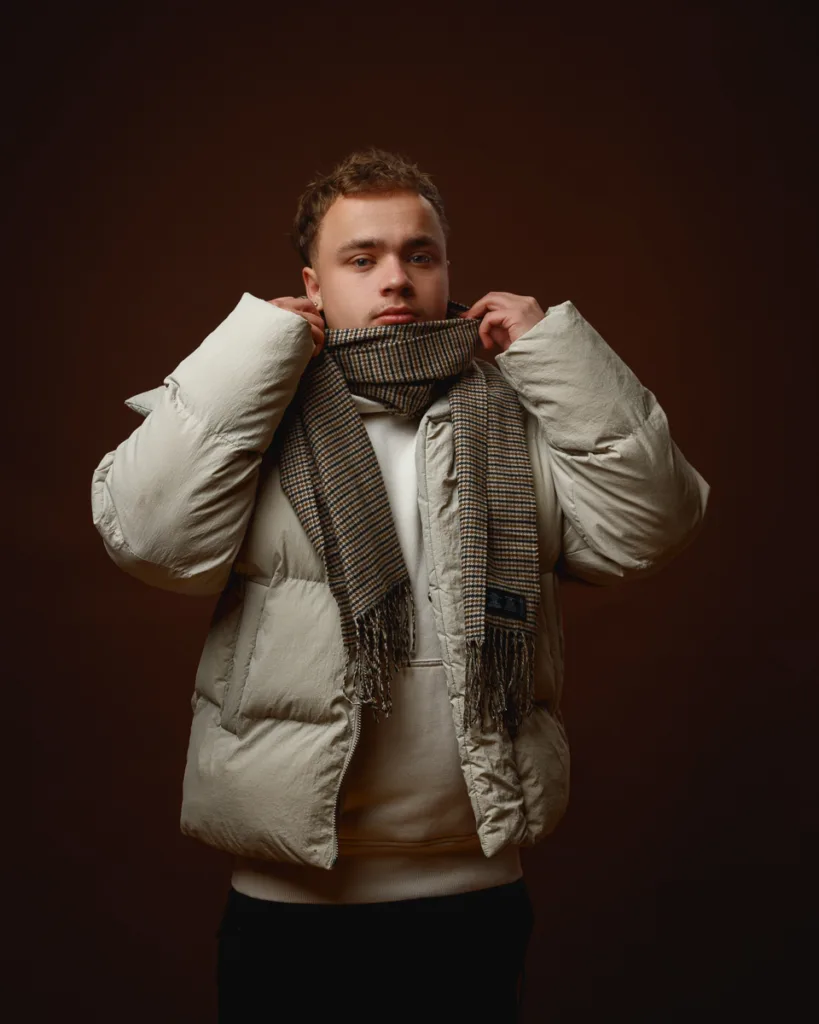 Person in puffer jacket with scarf indoors.
