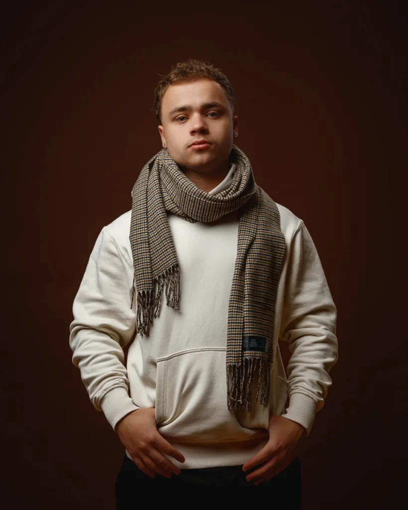 Man in white hoodie and scarf posing.
