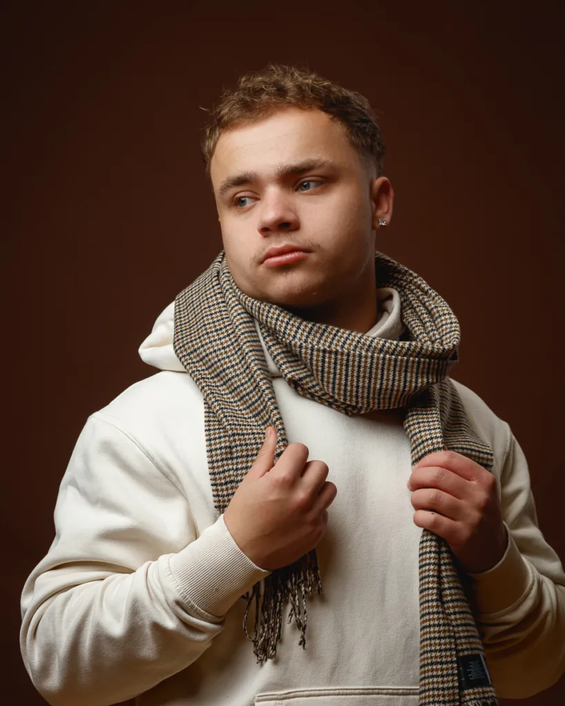 Person wearing scarf and hoodie, thoughtful expression.