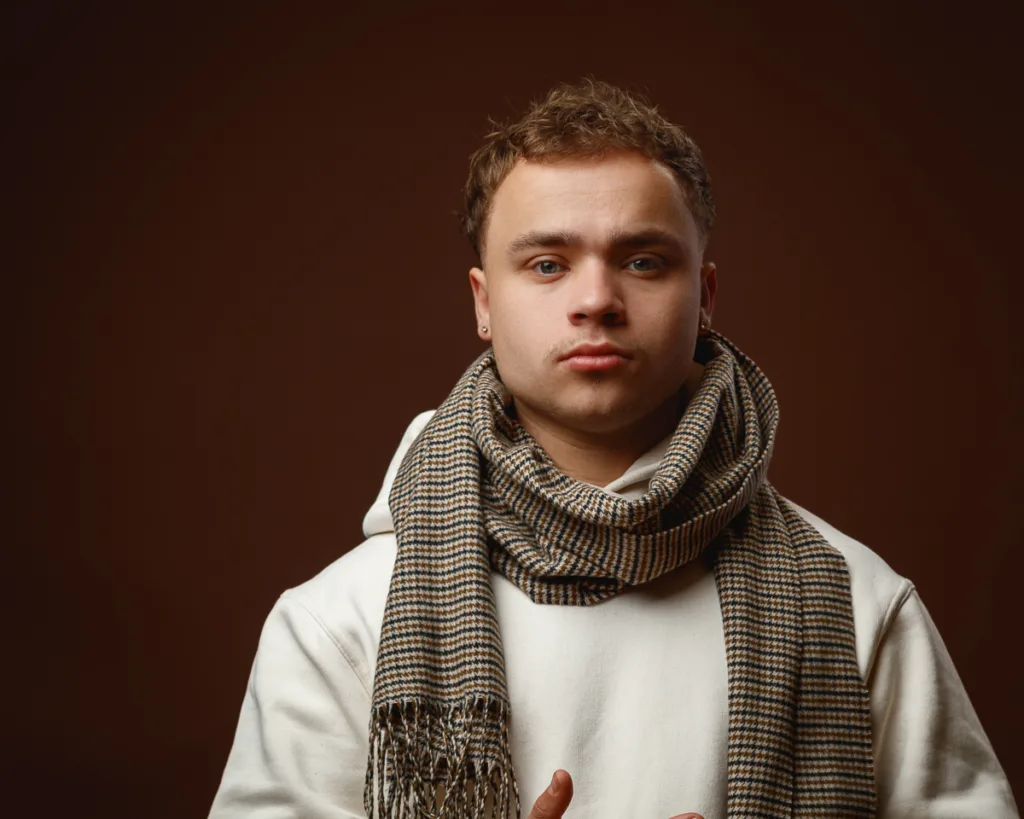 Young man wearing scarf and white jumper