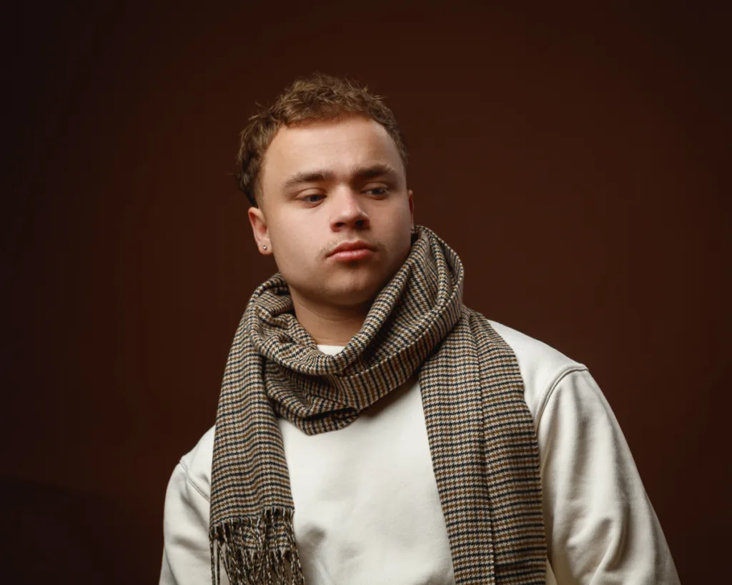 Man in scarf with brown background.