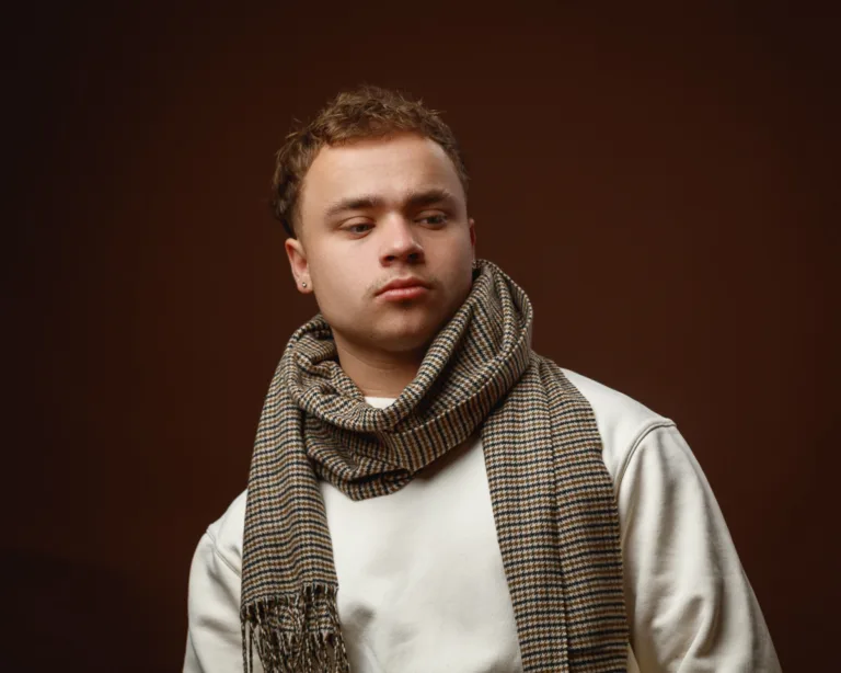 Man in scarf with brown background.