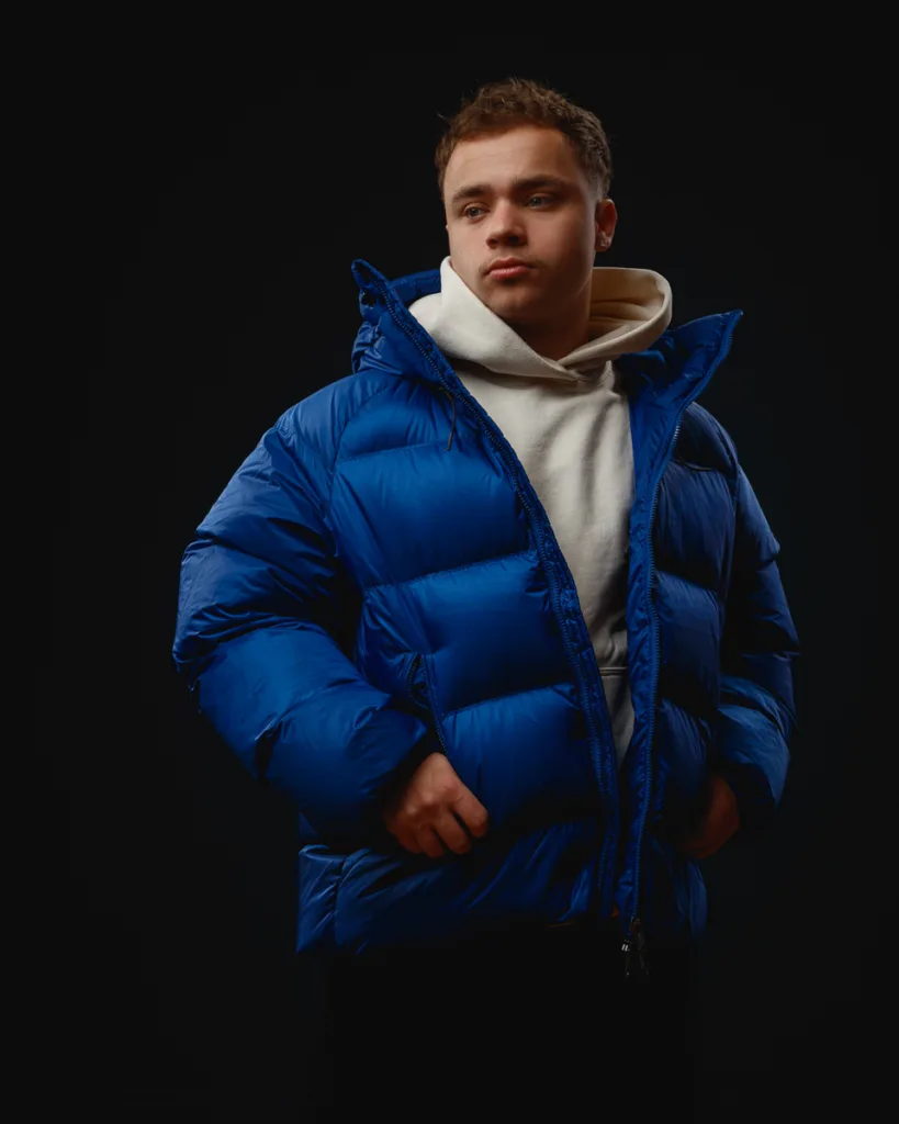 Person wearing blue puffer jacket and white hoodie.