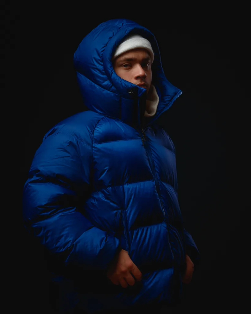 Person wearing blue puffer jacket, hood up.
