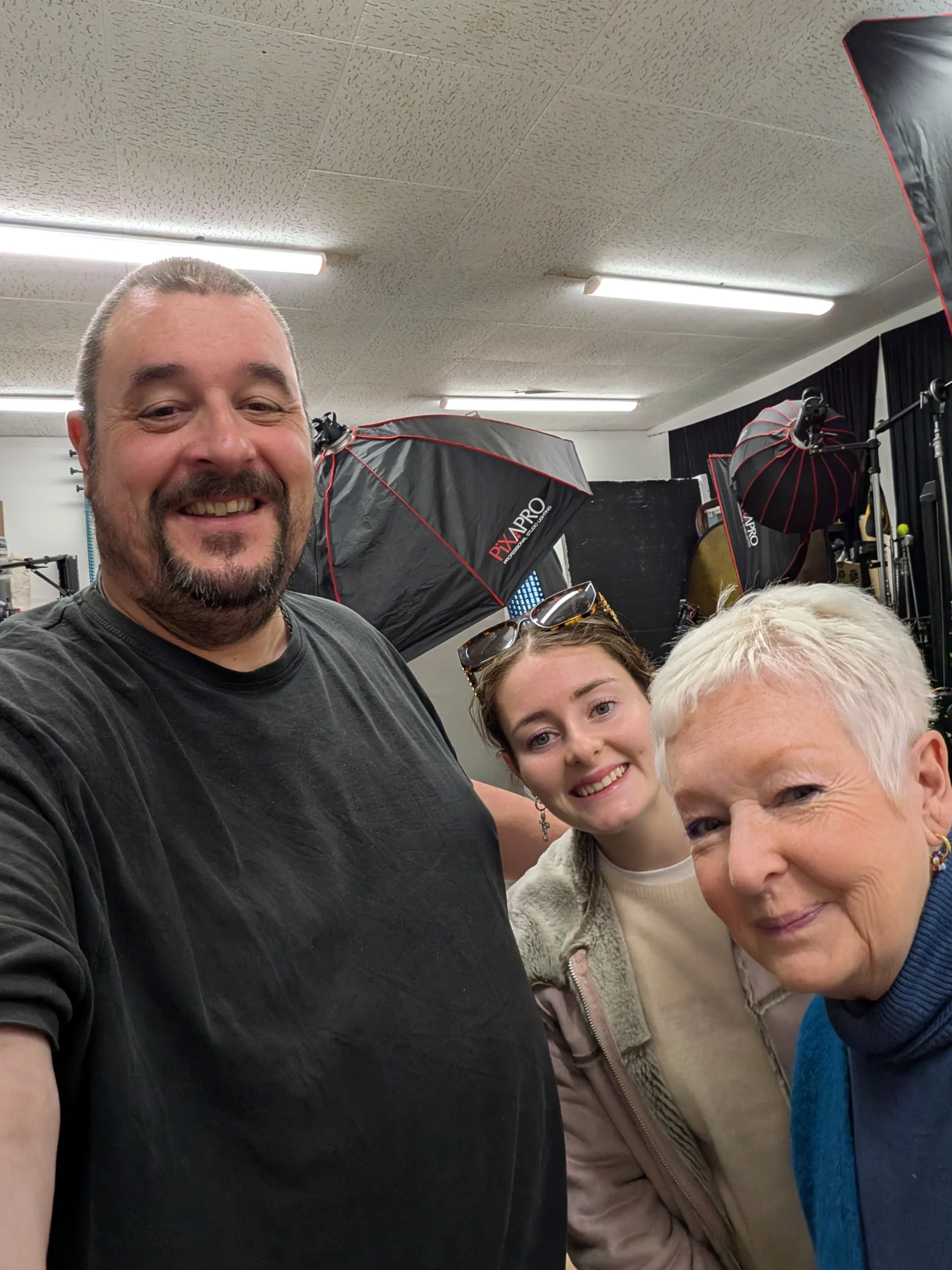 Three people smiling in a photography studio