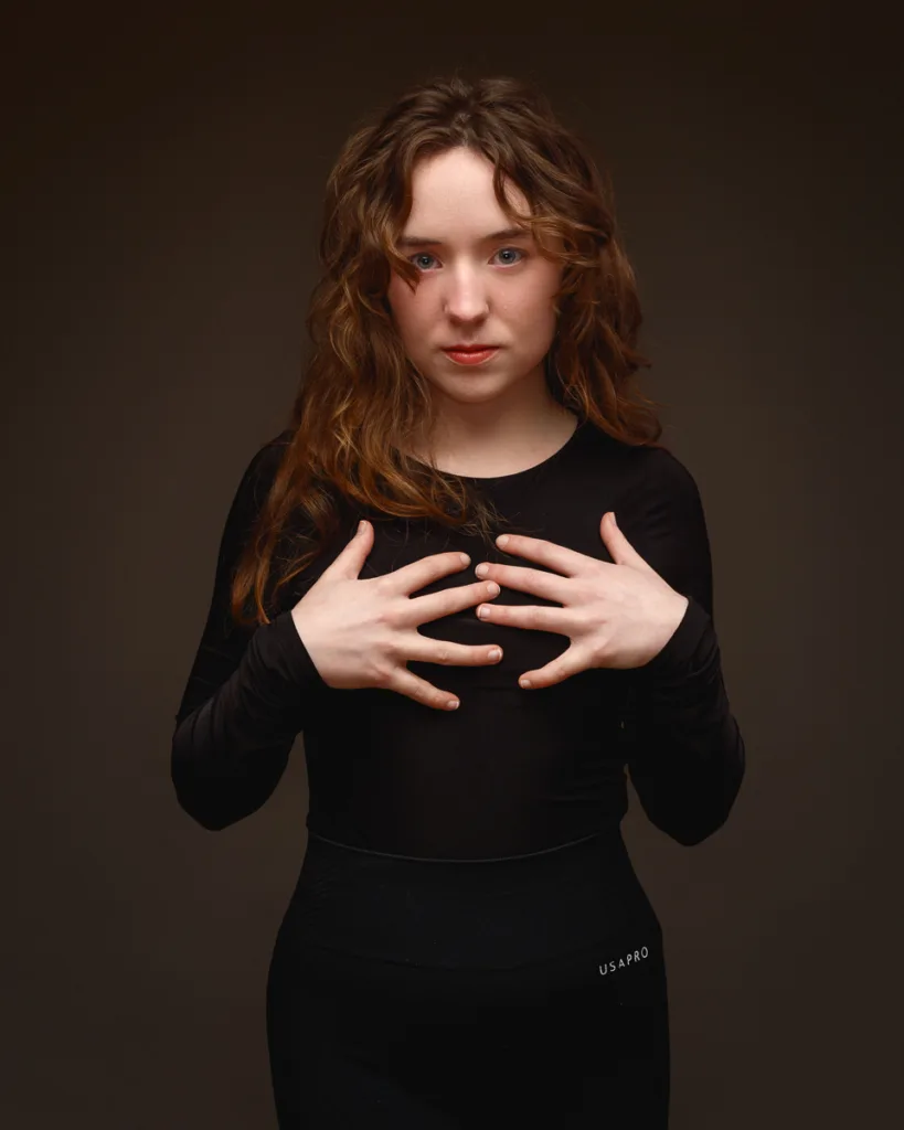 Woman posing in black outfit against dark background