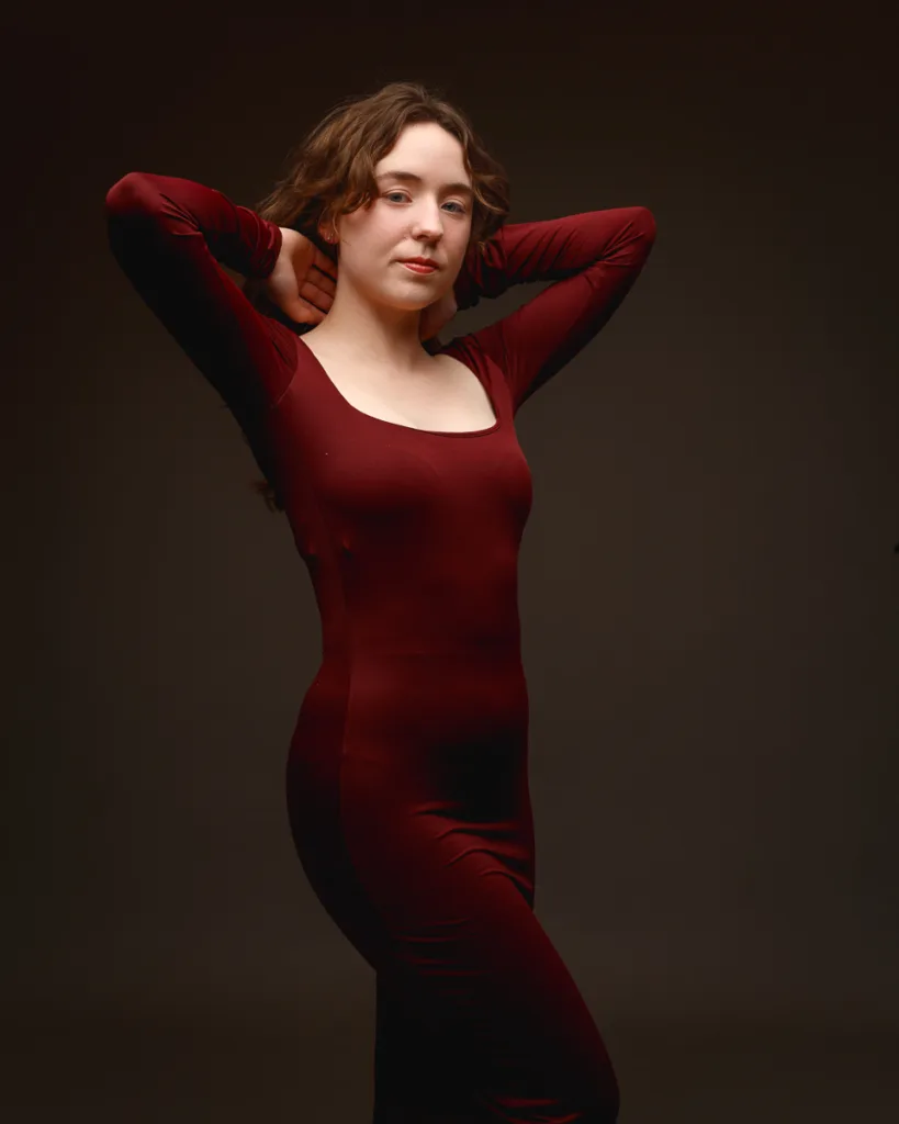 Person posing in red dress against dark background