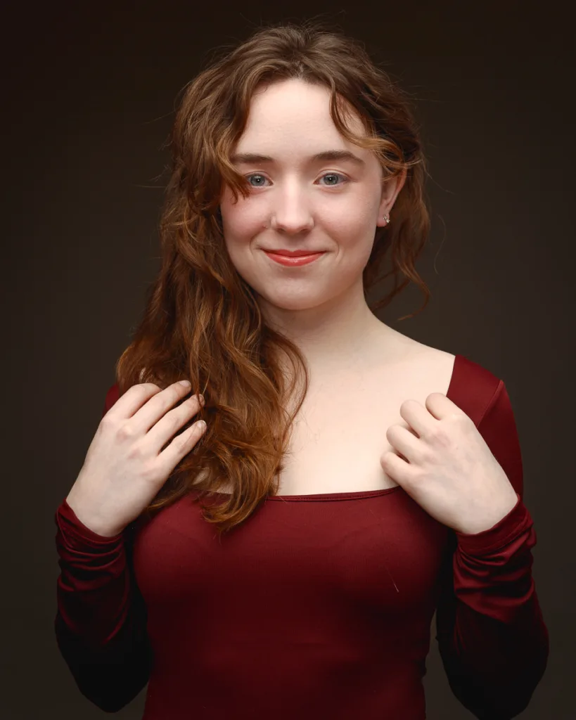 Smiling woman in red dress against dark background
