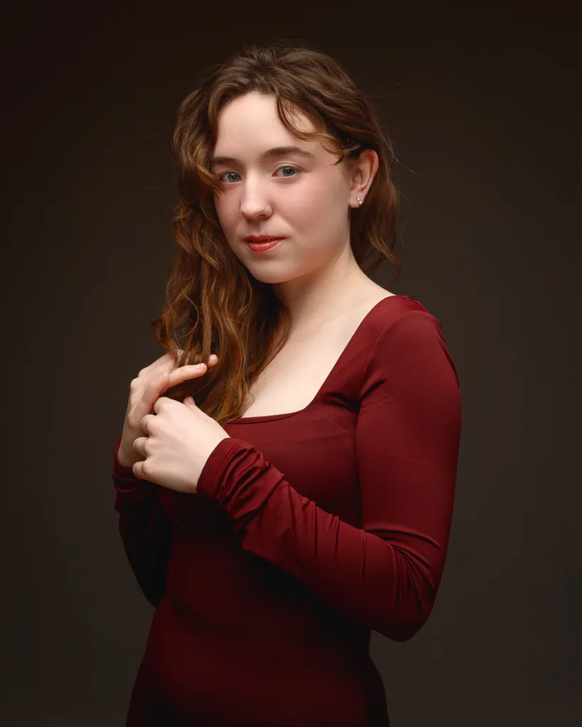 Woman in maroon dress posing against dark background