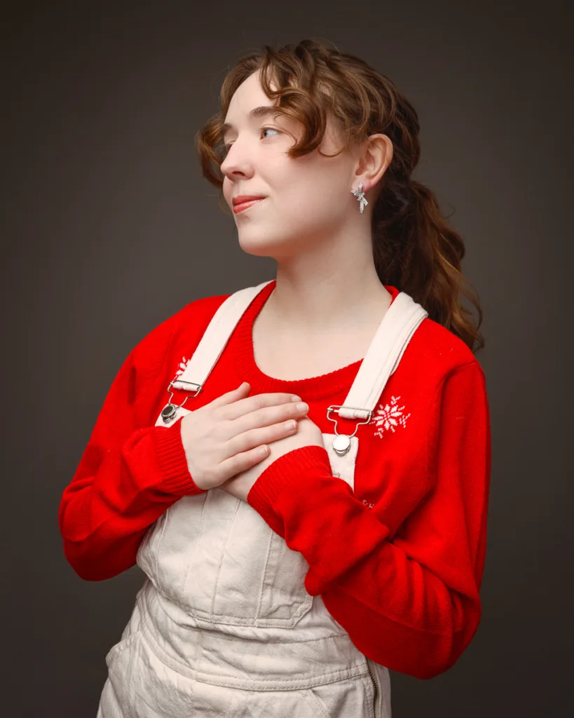 Person in red jumper and overalls smiling calmly