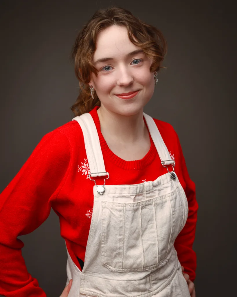 Smiling person in red jumper and beige overalls