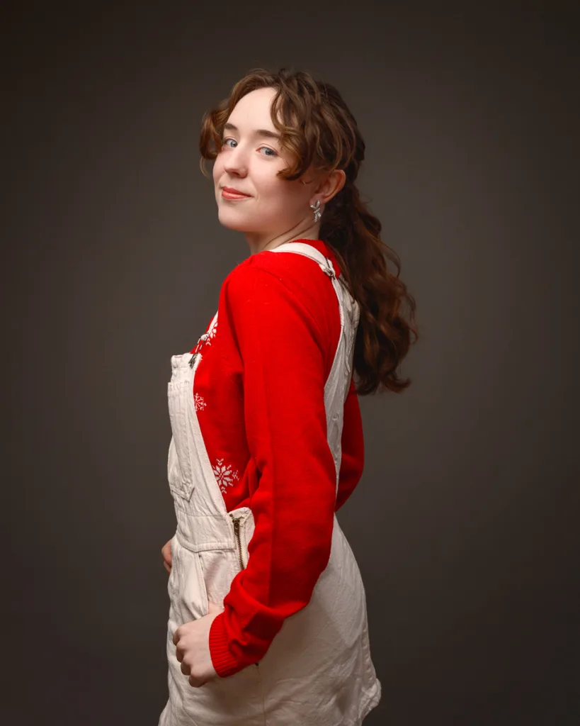 Person posing in red jumper and white overalls