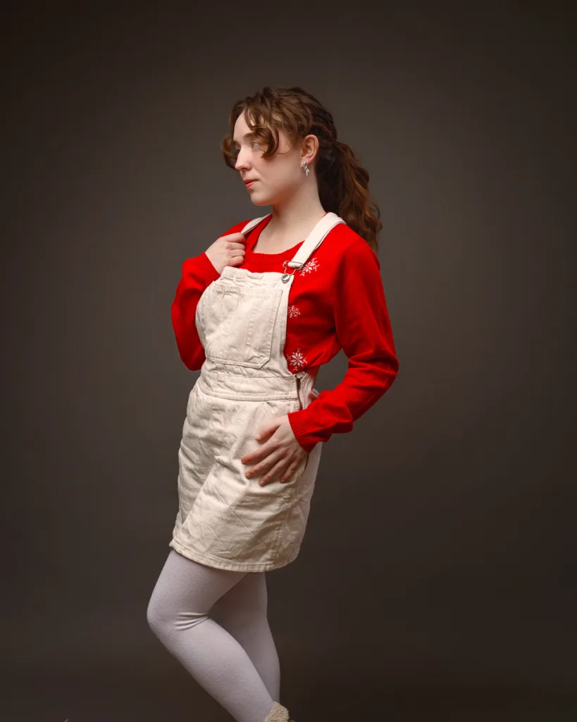 Person wearing red jumper and beige dungaree dress