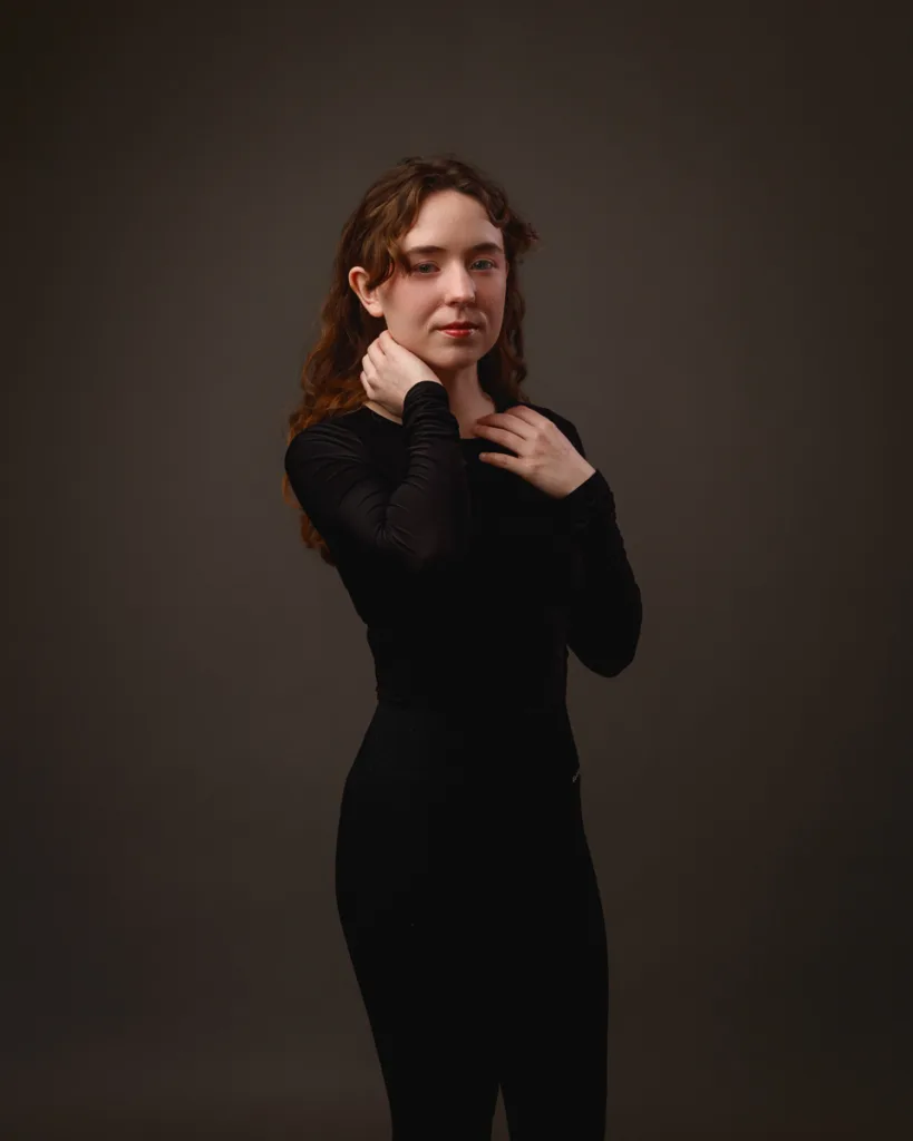 Person posing in black outfit against dark background