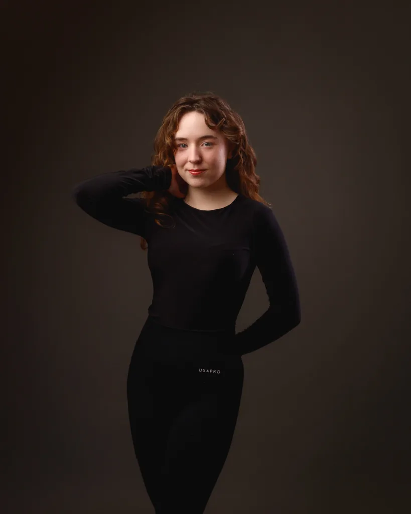 Person posing in black outfit against dark background