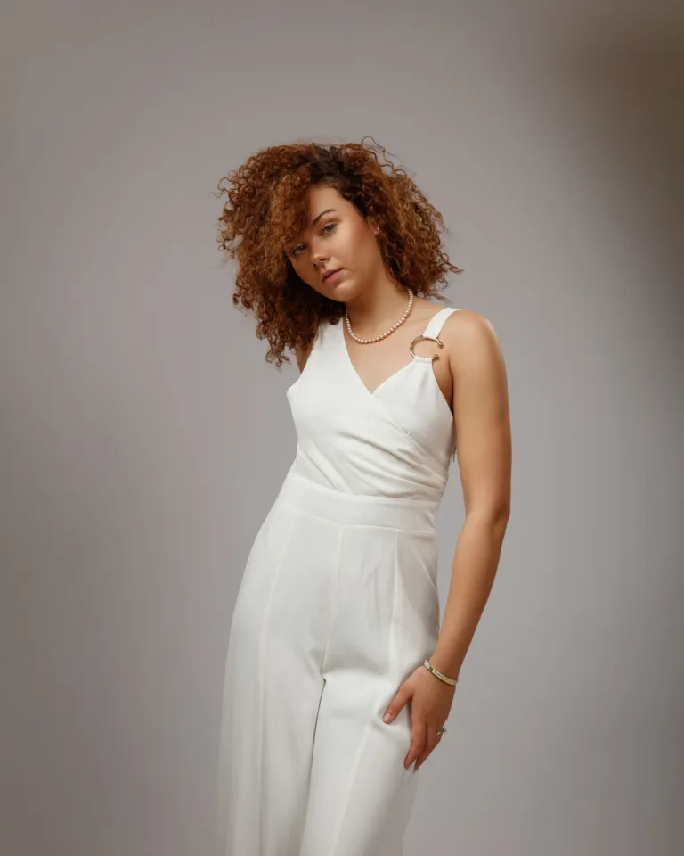 Woman wearing elegant white jumpsuit posing indoors