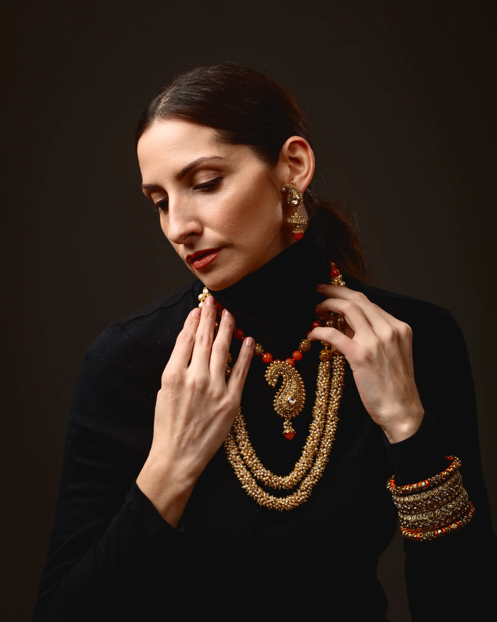 Woman wearing ornate jewellery, black outfit, elegant pose.