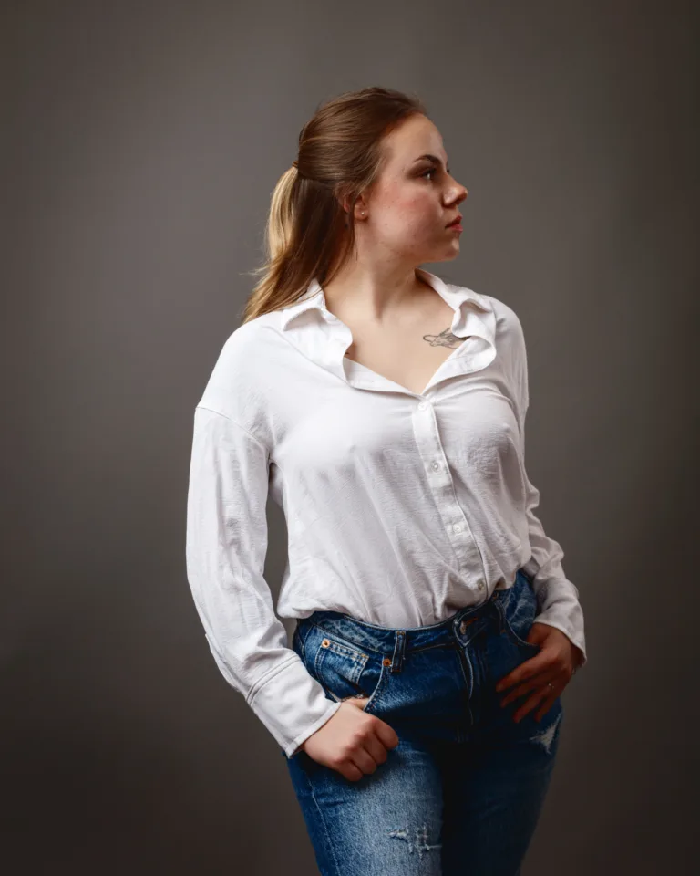 Woman in white shirt and jeans looking sideways.