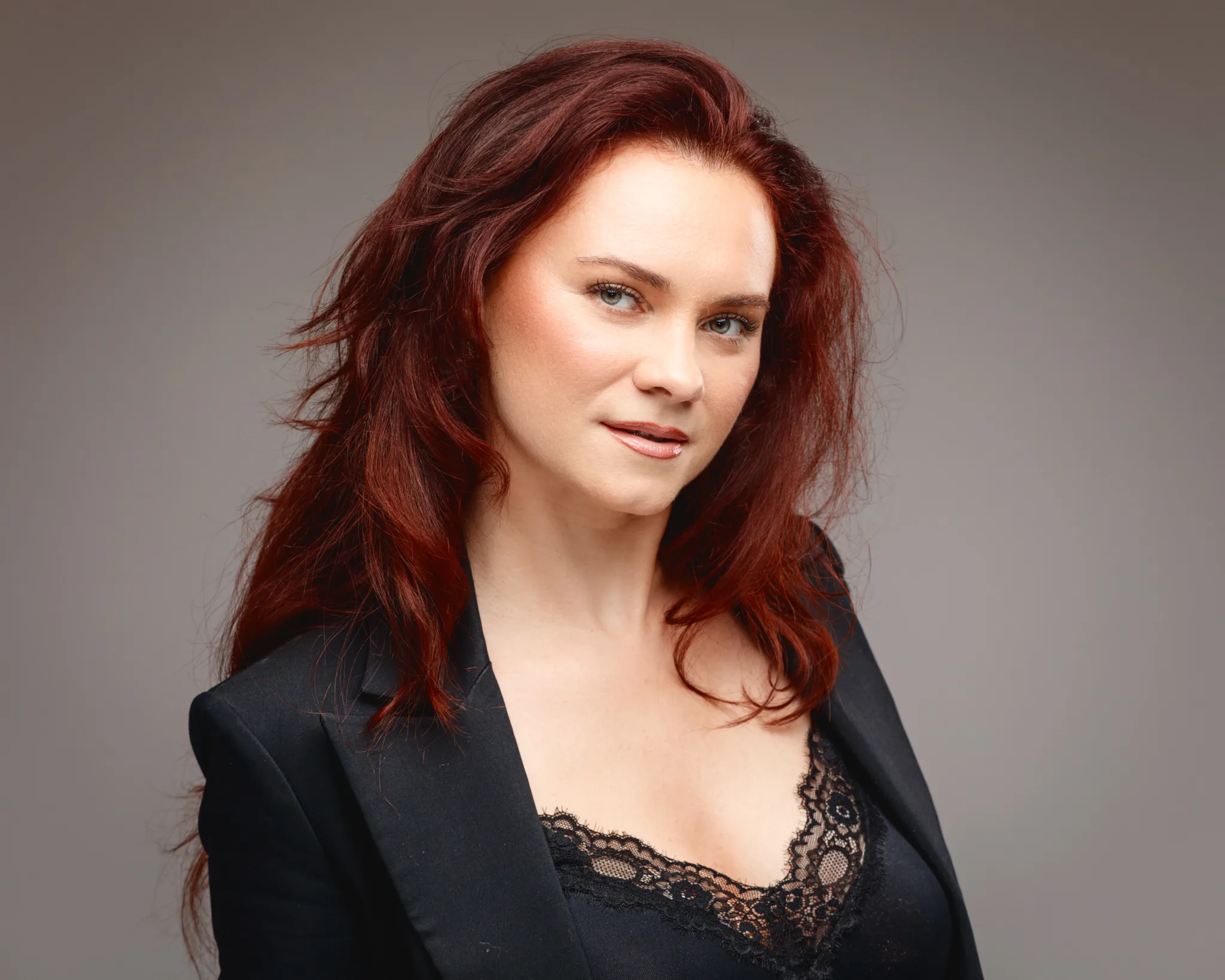 Woman with red hair in black lace attire.