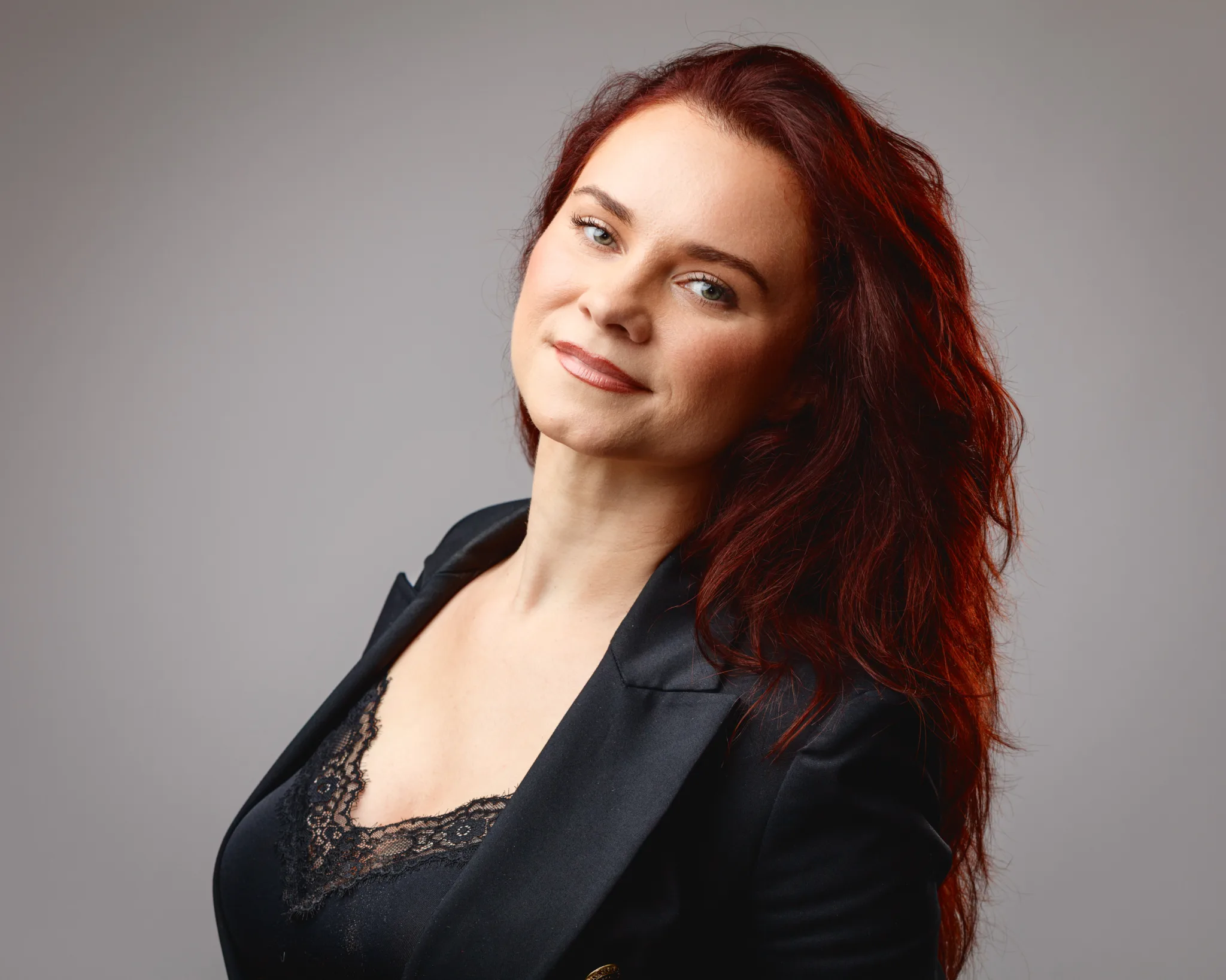 Woman with red hair in black jacket smiling.