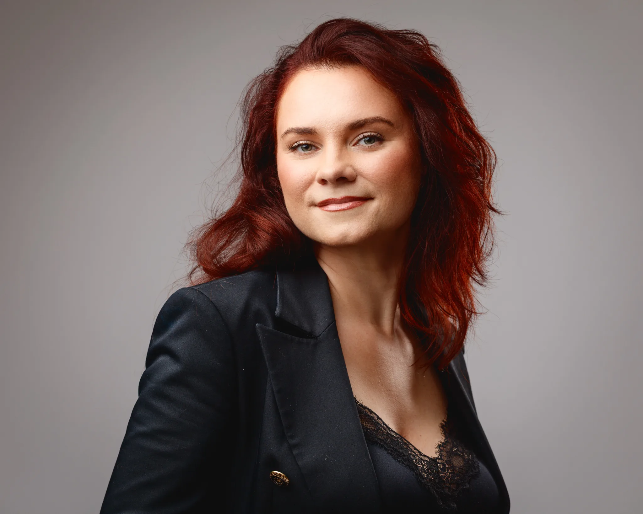 Confident woman with red hair in black suit.