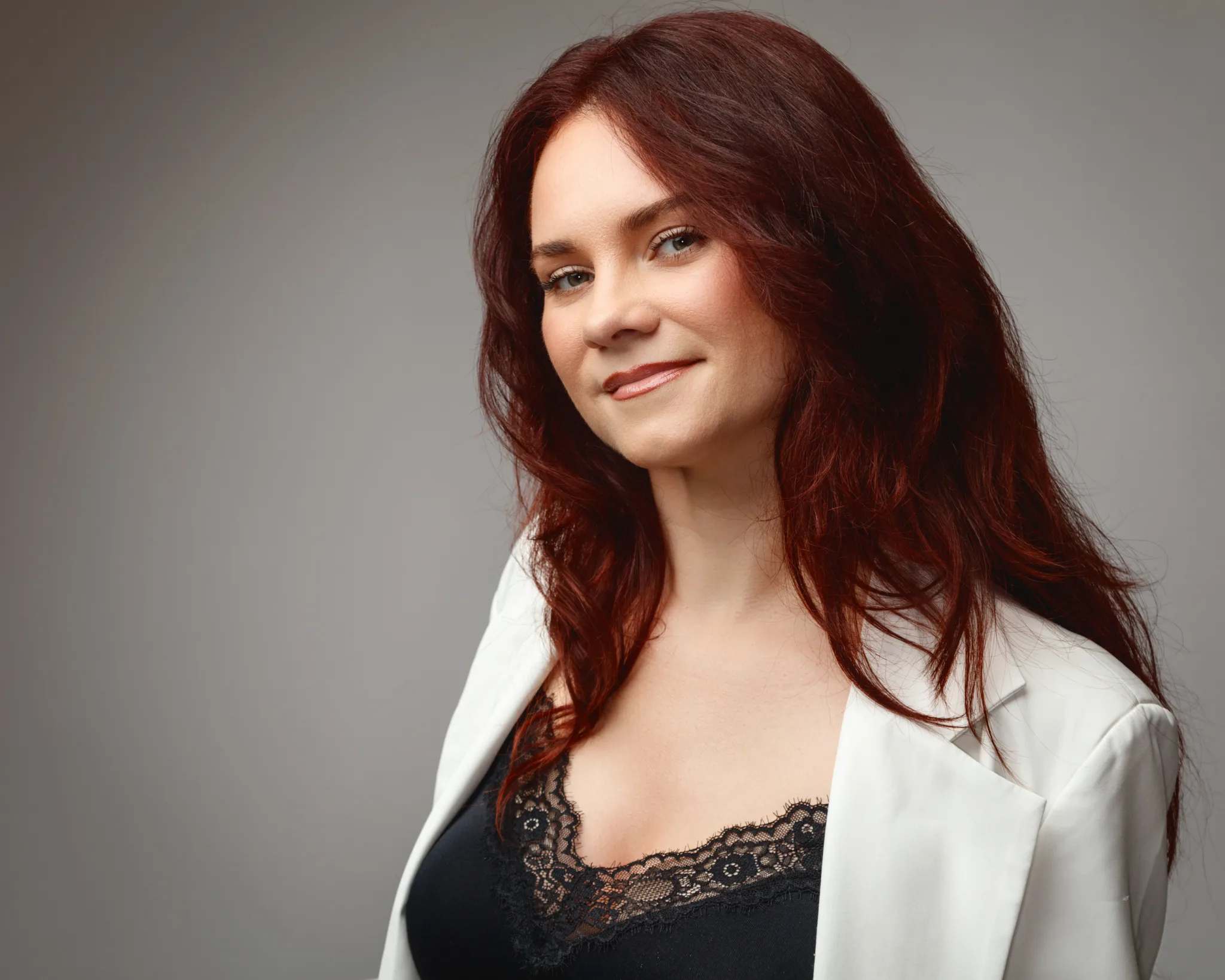 Smiling woman with red hair in white blazer