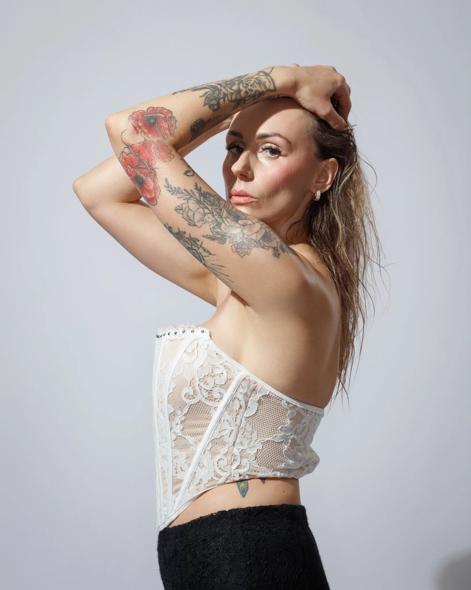 Woman with tattoos in lace top posing.