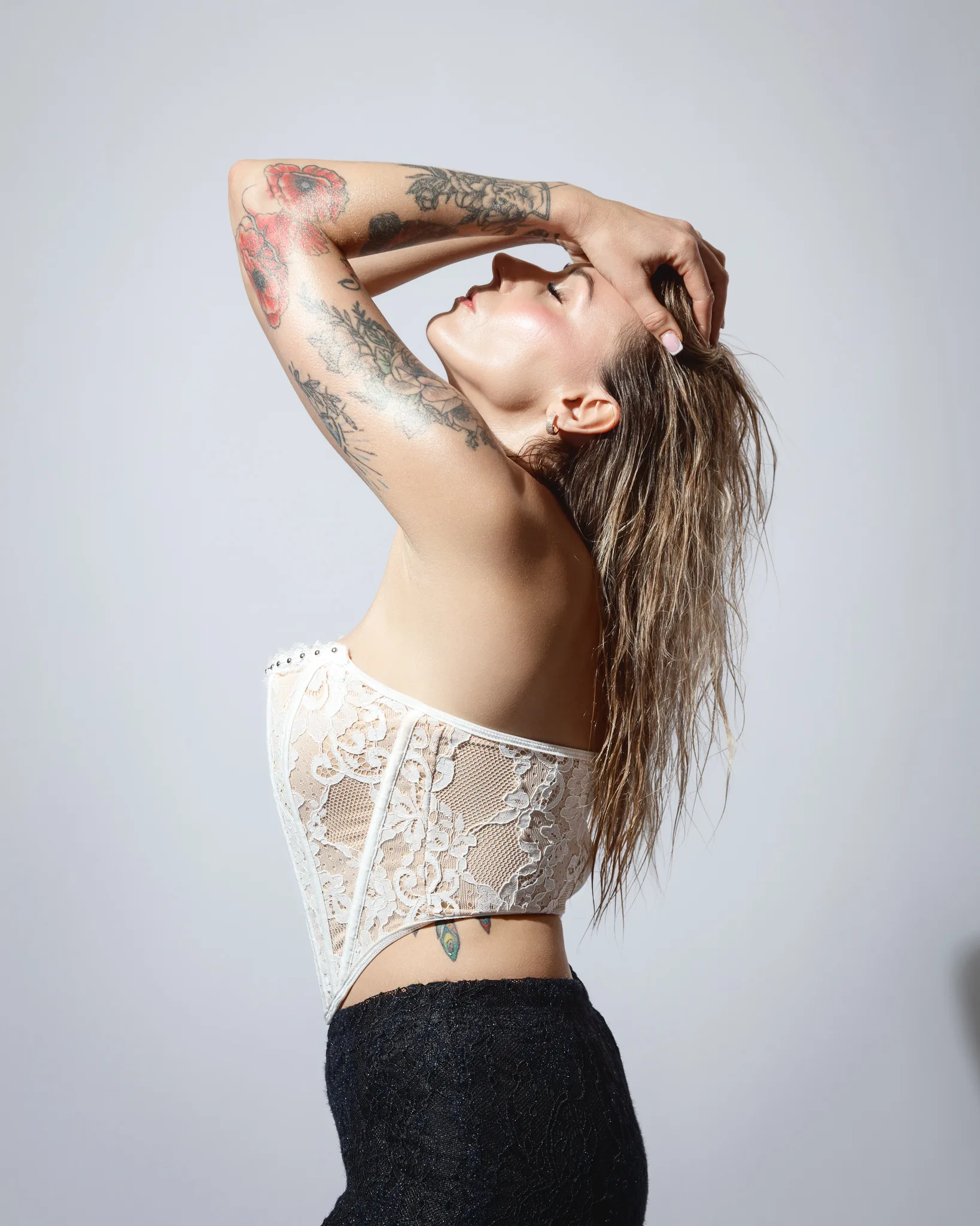 Tattooed model in lace top posing dramatically.