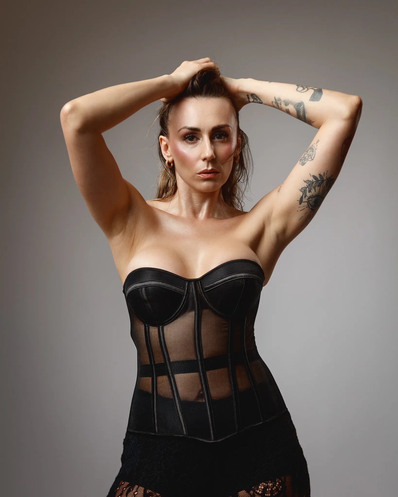 Model posing in black corset with tattoos.