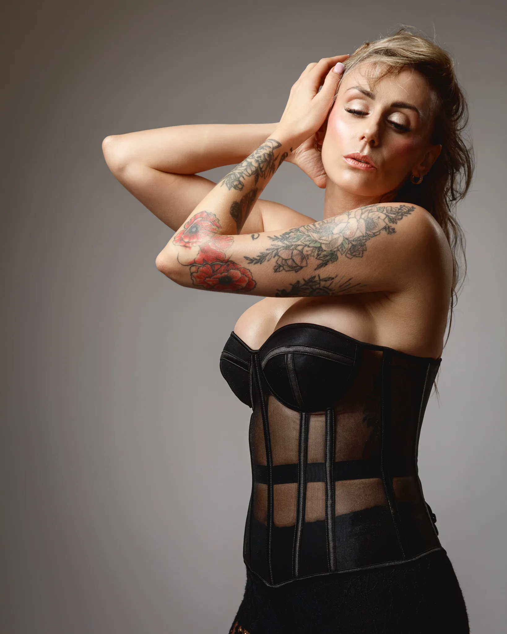 Tattooed woman in black corset posing confidently.