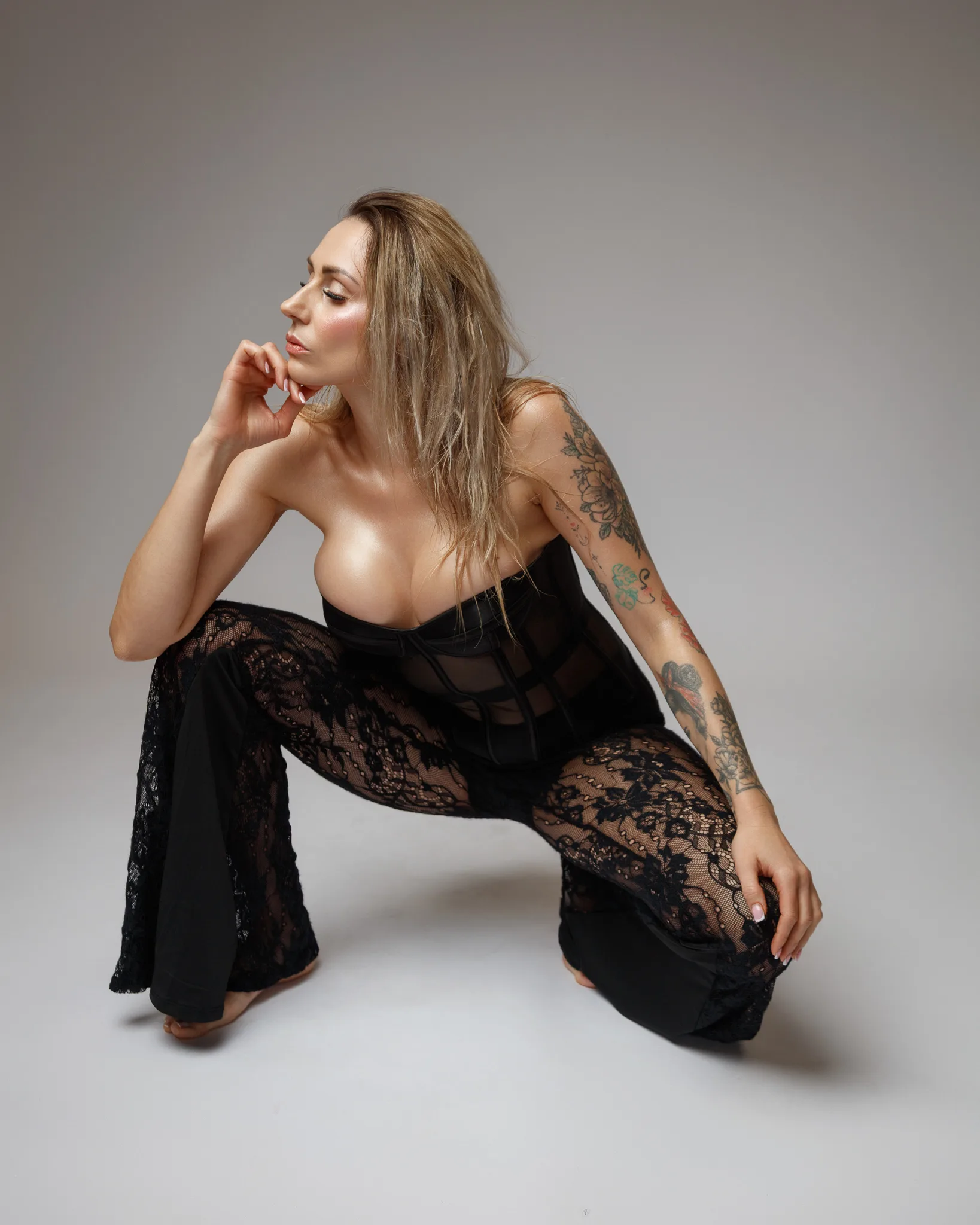 Woman in black lace fashion pose on studio floor.