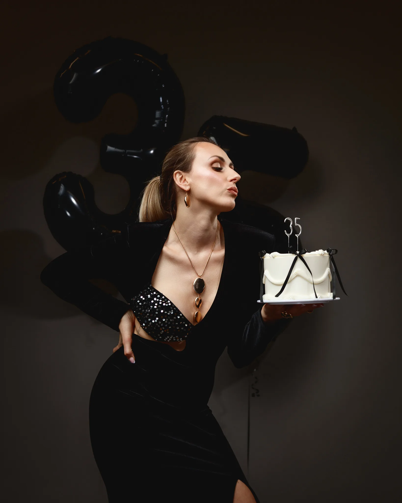 Woman celebrating 35th birthday with cake and balloons.