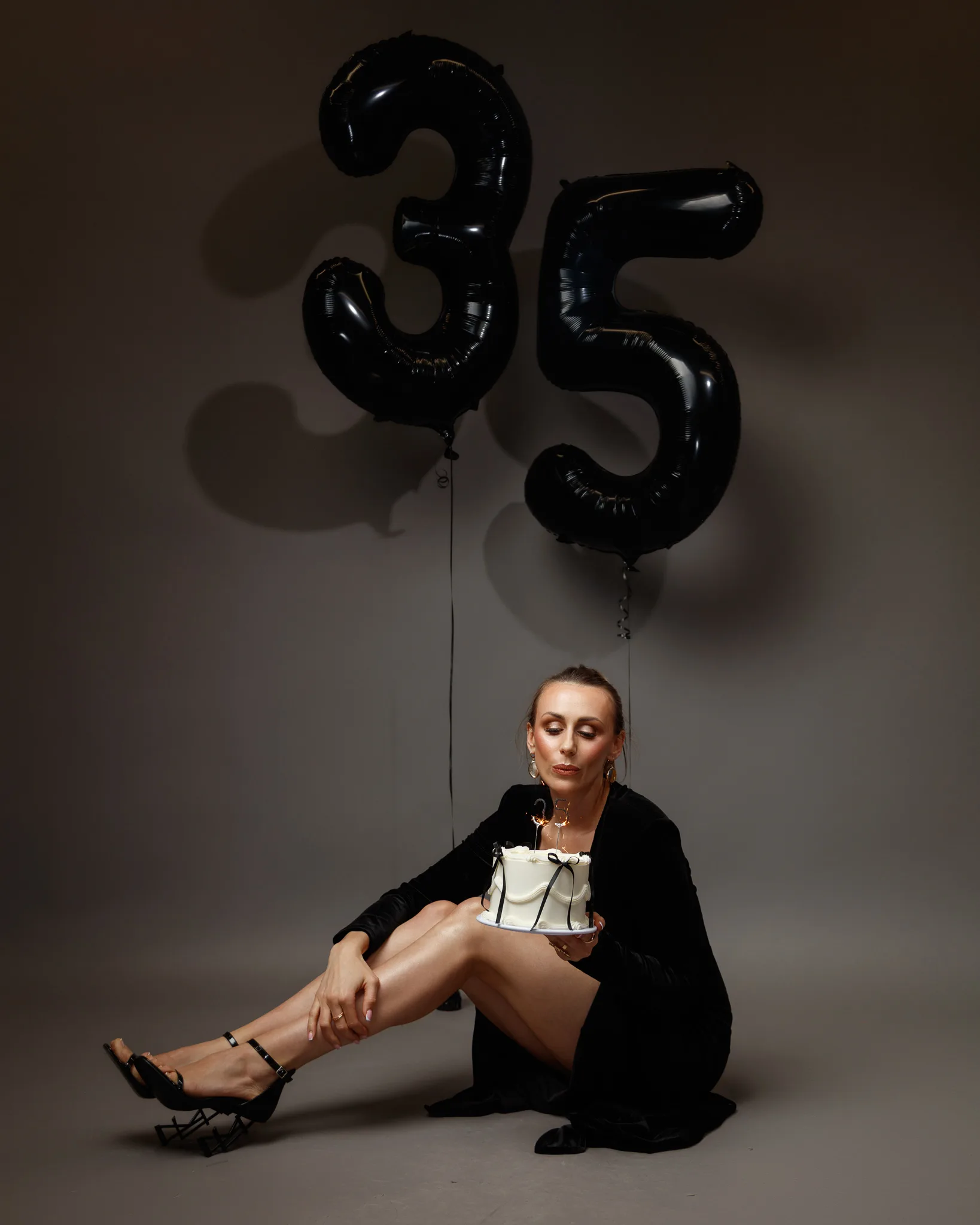 Woman with cake and '35' balloons celebrating birthday.
