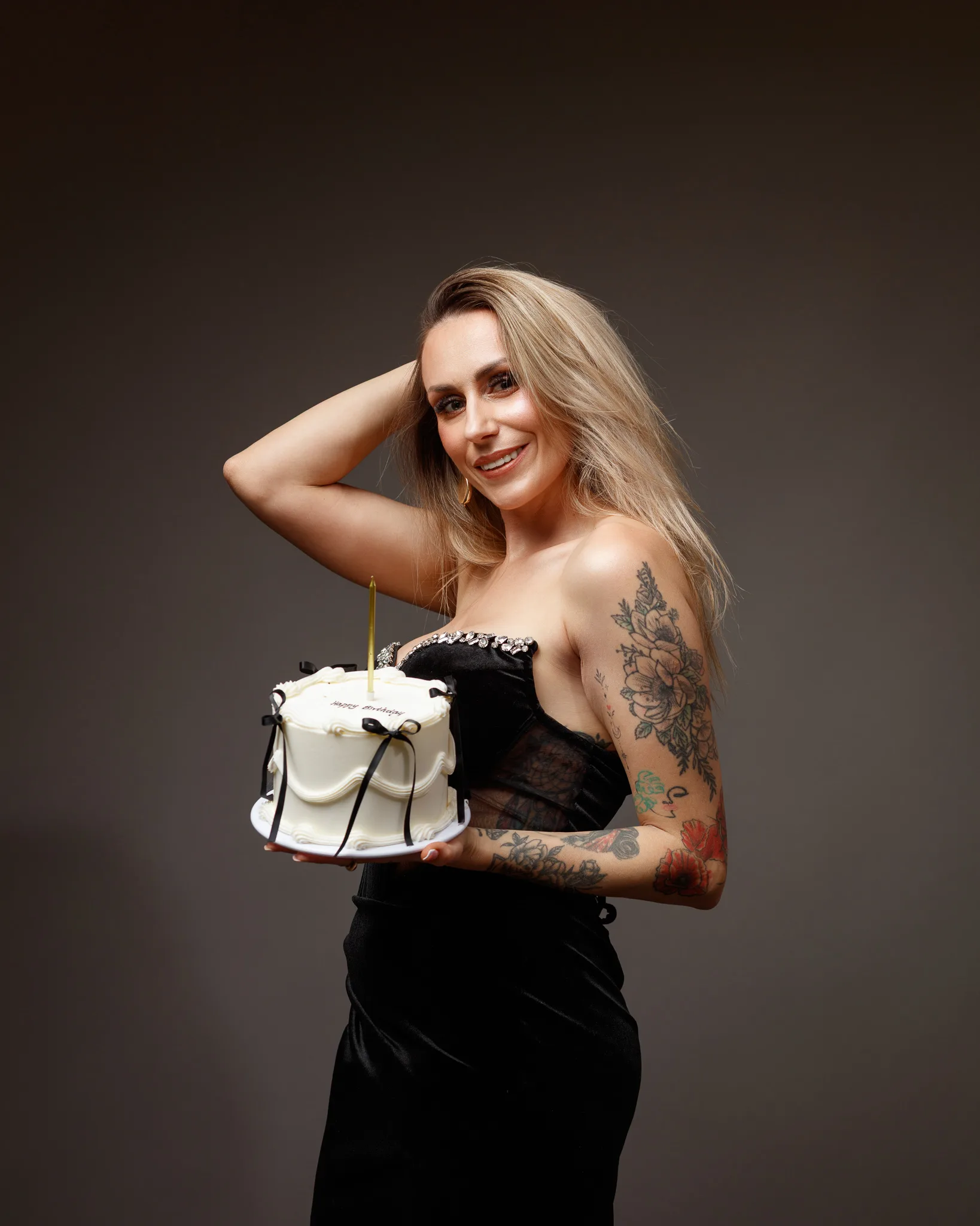 Smiling woman with tattoos holding birthday cake